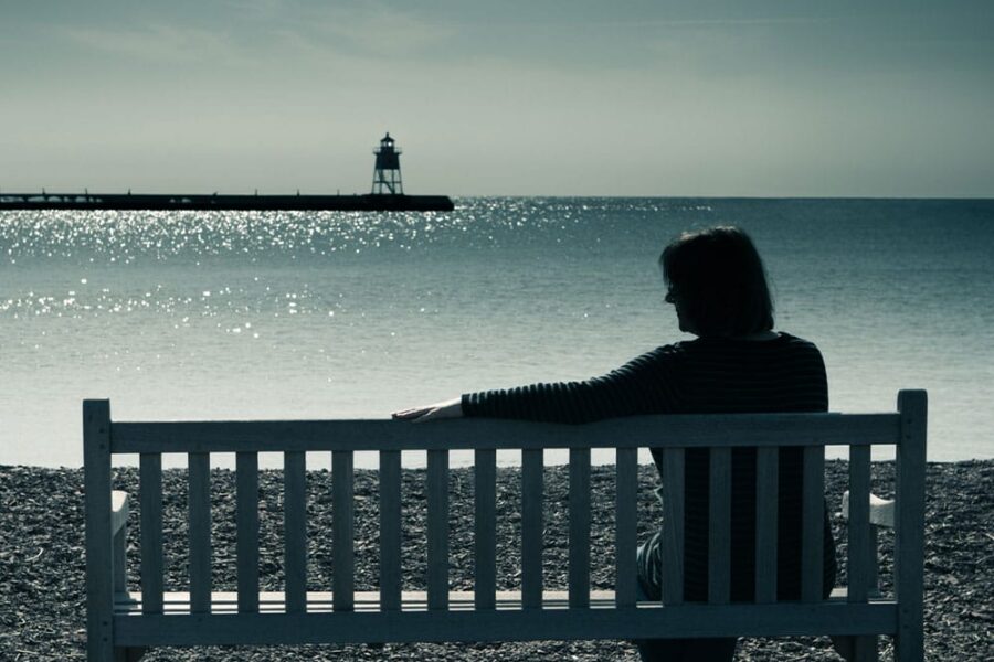 older woman on a bench at the beach in Roseville, CA, after her spouse passed away